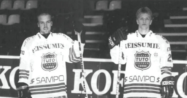 Kaksi TUTO Hockeyn pelaajaa seisoo jäähallissa Reissumies-pelipaidoissa. Kuvassa Antti Virtanen (#42) ja Timo Pärssinen (#27). Mustavalkoinen kuva 1990-luvulta.