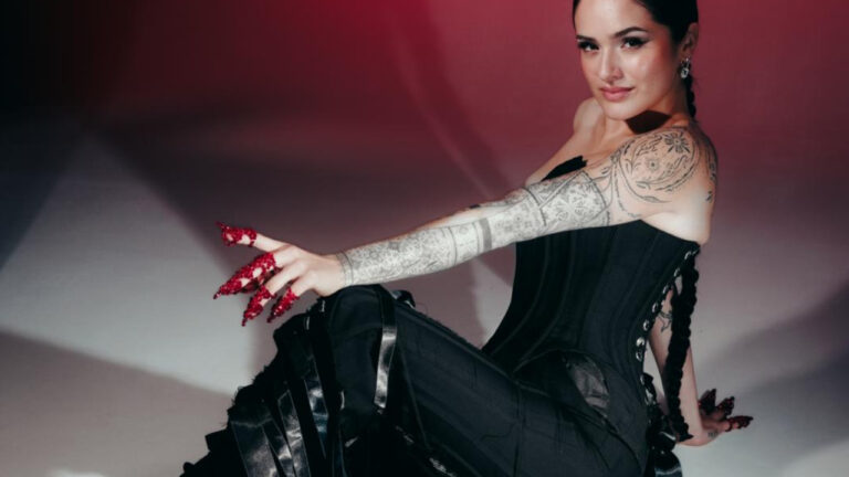 Chachi poseeraa mustassa asussa UMK 2026 -promokuvassa, punaiset kynnet ja tatuoitu käsivarsi korostavat ilmettä.